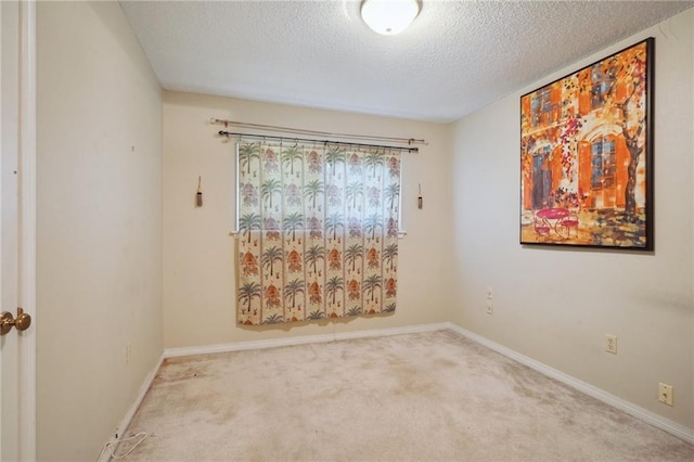 carpeted empty room with baseboards and a textured ceiling