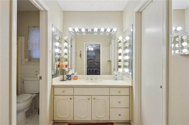 bathroom featuring vanity, tile walls, toilet, and tile patterned flooring