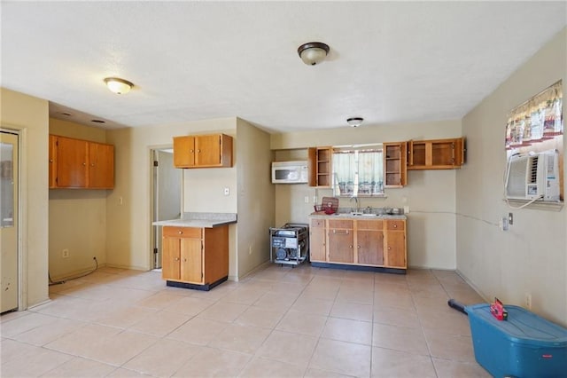 kitchen with brown cabinetry, white microwave, open shelves, light tile patterned flooring, and light countertops