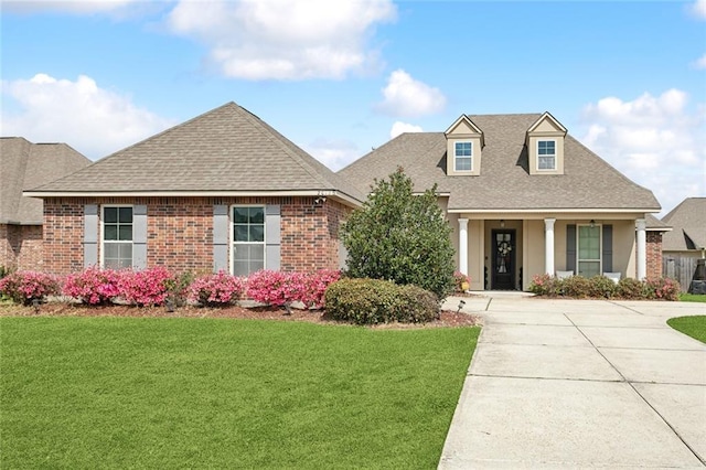 view of front of home with a front yard, brick siding, and a shingled roof