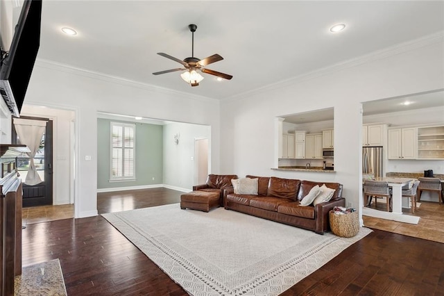 living area with ornamental molding, ceiling fan, and dark wood-style flooring