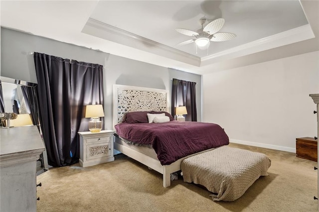 carpeted bedroom with a tray ceiling, baseboards, ceiling fan, and crown molding