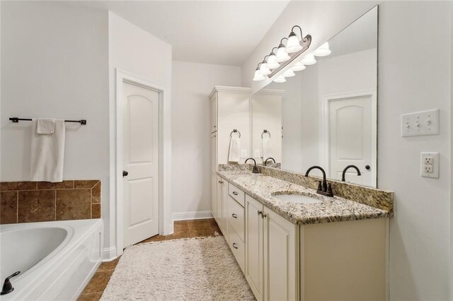 bathroom with a sink, baseboards, a bath, and double vanity