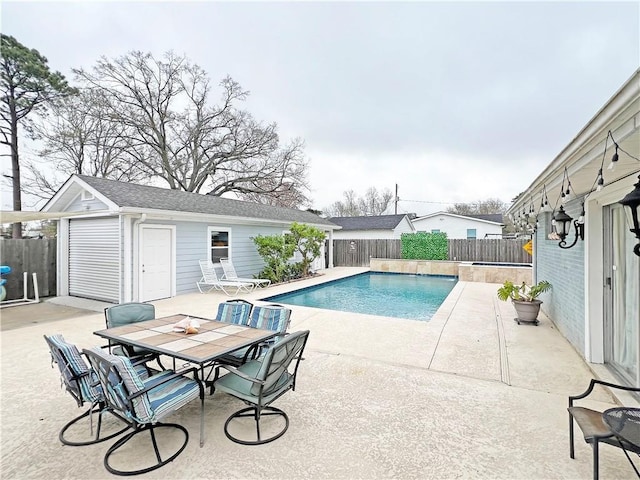 view of swimming pool featuring an outbuilding, a fenced in pool, outdoor dining area, a fenced backyard, and a patio area