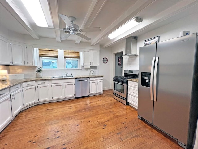 kitchen with beam ceiling, stainless steel appliances, light wood-style floors, white cabinetry, and wall chimney exhaust hood