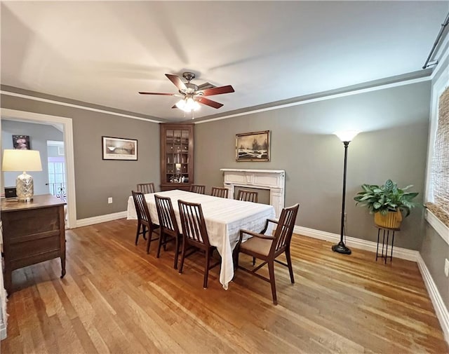 dining area featuring light wood-type flooring, baseboards, ceiling fan, and ornamental molding