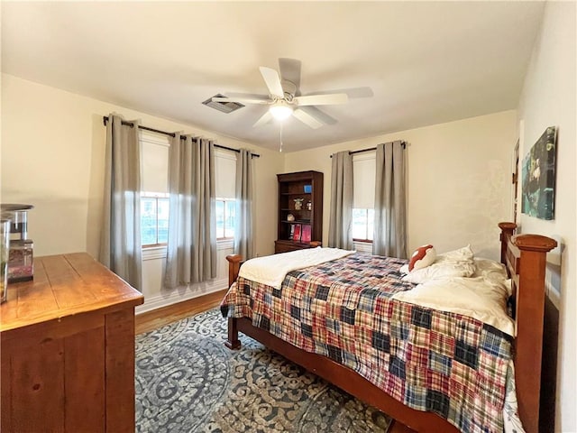 bedroom with ceiling fan, visible vents, and wood finished floors