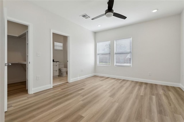 unfurnished bedroom with light wood-type flooring, visible vents, baseboards, and a spacious closet