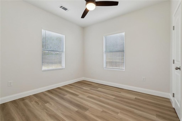 empty room featuring visible vents, baseboards, light wood-style floors, and a ceiling fan