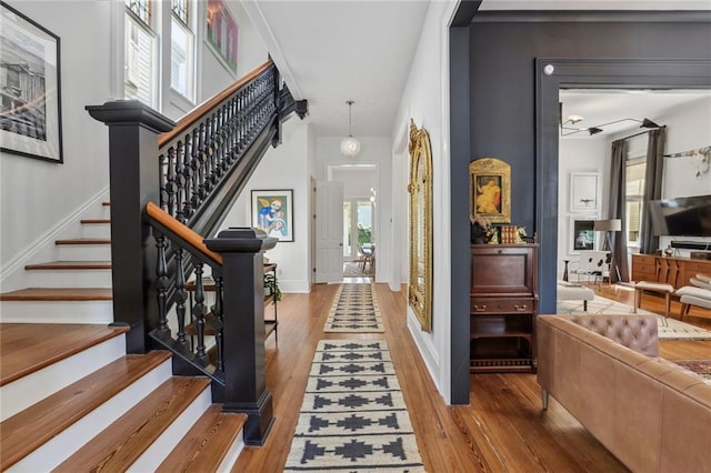 foyer entrance with stairs, baseboards, and wood-type flooring