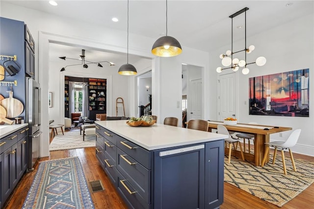 kitchen with visible vents, a center island, dark wood-type flooring, pendant lighting, and light countertops