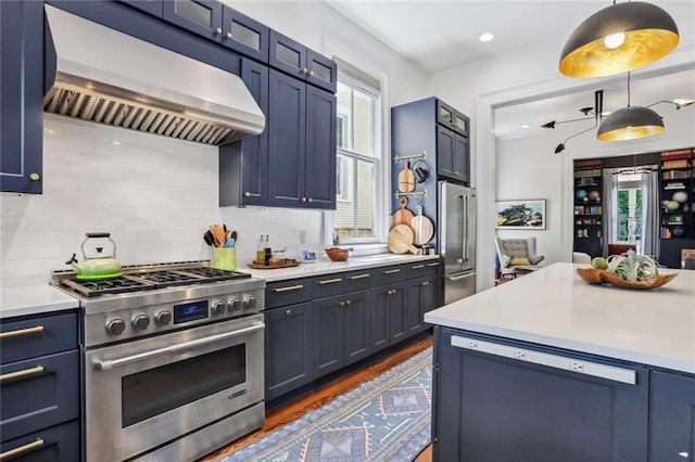 kitchen with tasteful backsplash, dark wood finished floors, light countertops, range hood, and high end appliances