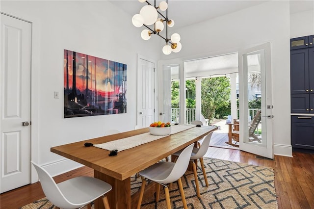 dining space featuring a notable chandelier, baseboards, and hardwood / wood-style flooring