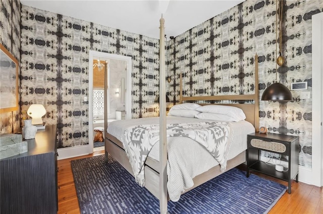 bedroom with wallpapered walls, wood finished floors, and baseboards