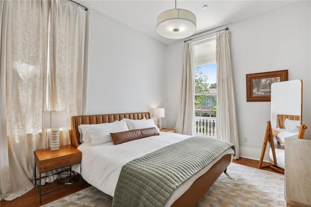 bedroom with access to exterior, wood finished floors, and baseboards