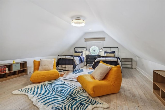 bedroom with baseboards, lofted ceiling, and hardwood / wood-style flooring