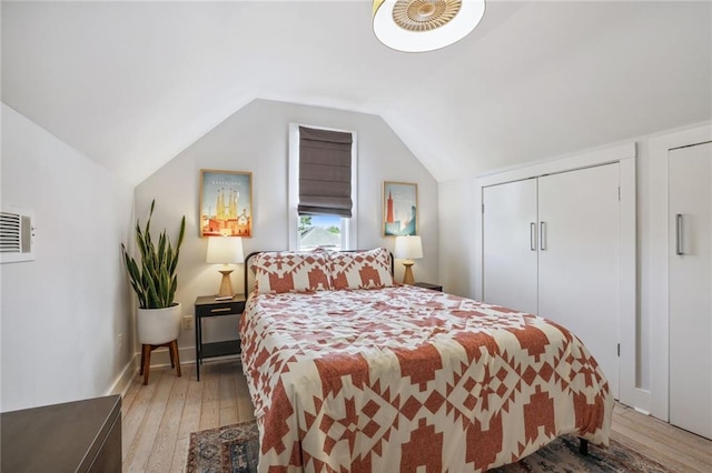 bedroom with light wood finished floors, baseboards, and lofted ceiling