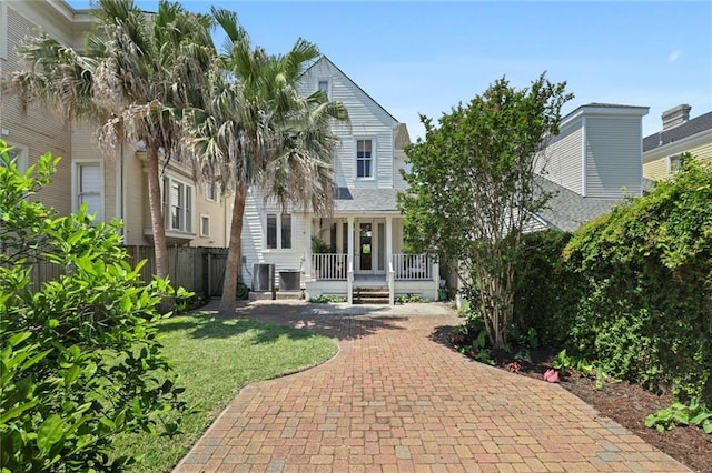 rear view of house with a yard, covered porch, and fence