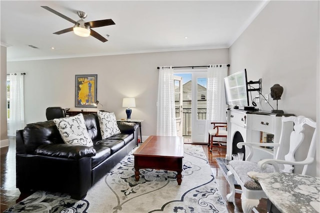 living room with ceiling fan, visible vents, wood finished floors, and crown molding