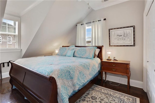 bedroom with a closet, dark wood finished floors, lofted ceiling, and baseboards