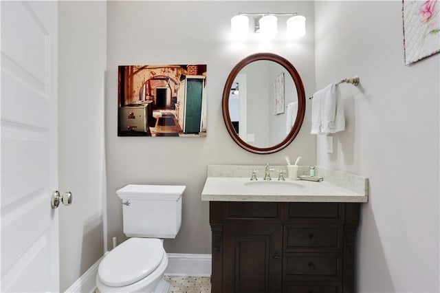 half bathroom featuring toilet, vanity, and baseboards