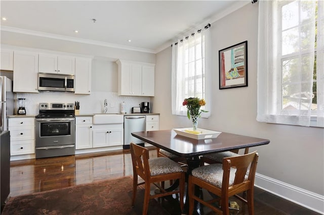 kitchen featuring a sink, crown molding, backsplash, and stainless steel appliances