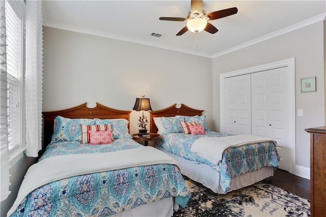 bedroom with wood finished floors, visible vents, ornamental molding, a closet, and multiple windows