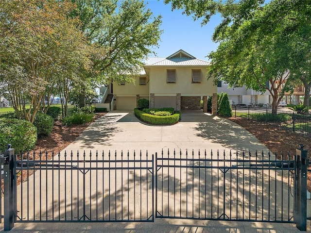 view of front of house with stucco siding, concrete driveway, stone siding, a garage, and a fenced front yard