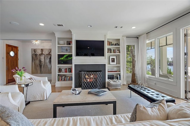 living room featuring visible vents, recessed lighting, a warm lit fireplace, and wood finished floors