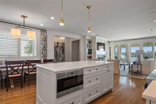 kitchen featuring light countertops, decorative light fixtures, plenty of natural light, and wood finished floors