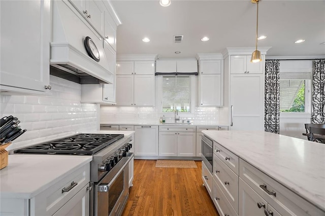 kitchen featuring premium range hood, visible vents, a sink, white cabinetry, and stainless steel appliances