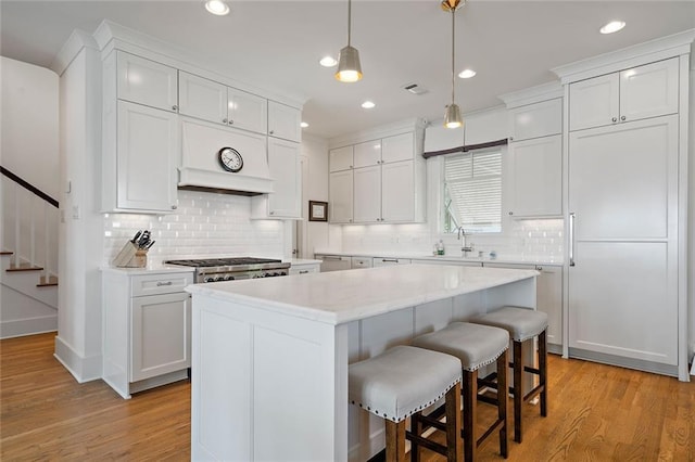 kitchen featuring premium range hood, a breakfast bar area, a center island, and white cabinetry