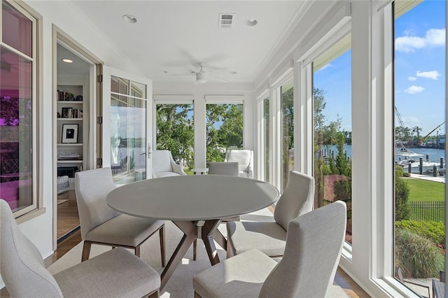 sunroom featuring visible vents, plenty of natural light, ceiling fan, and a water view