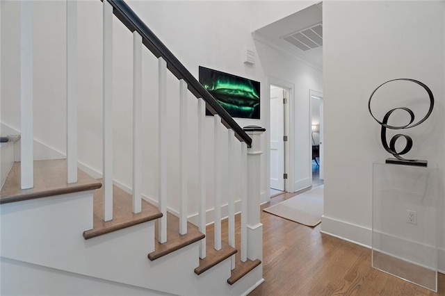 staircase featuring visible vents, baseboards, and wood finished floors