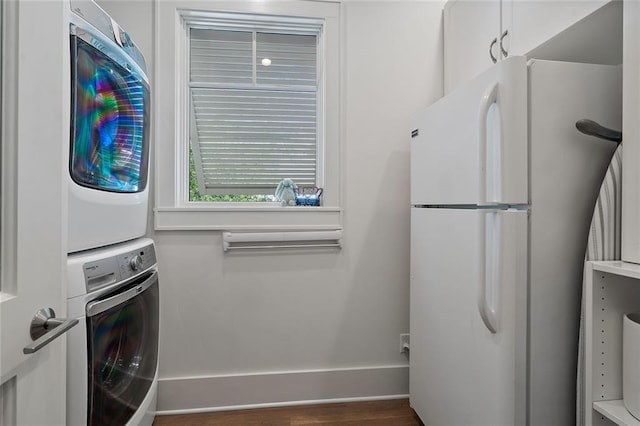 laundry room with baseboards, wood finished floors, laundry area, and stacked washing maching and dryer