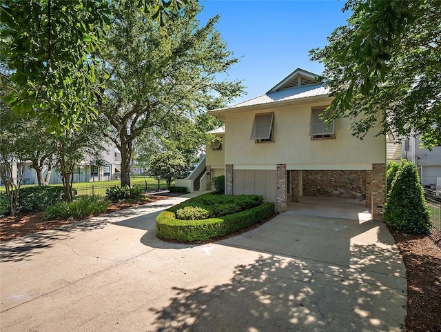 view of front facade featuring stairway, an attached garage, stucco siding, concrete driveway, and metal roof