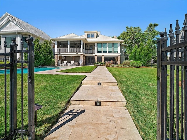 back of house featuring a lawn, metal roof, a patio area, stone siding, and an outdoor pool