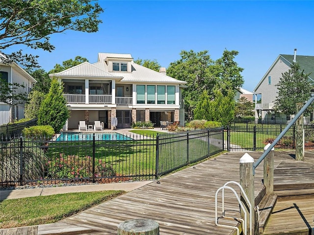 rear view of house featuring a fenced in pool, metal roof, a yard, and fence