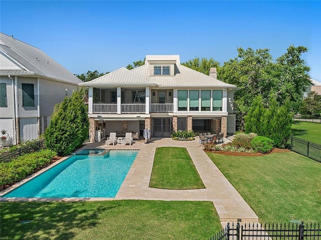 back of house with a yard, a fenced backyard, a chimney, a patio area, and metal roof