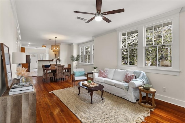 living room featuring visible vents, ornamental molding, a ceiling fan, wood-type flooring, and baseboards