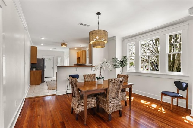 dining area with baseboards, visible vents, and wood-type flooring