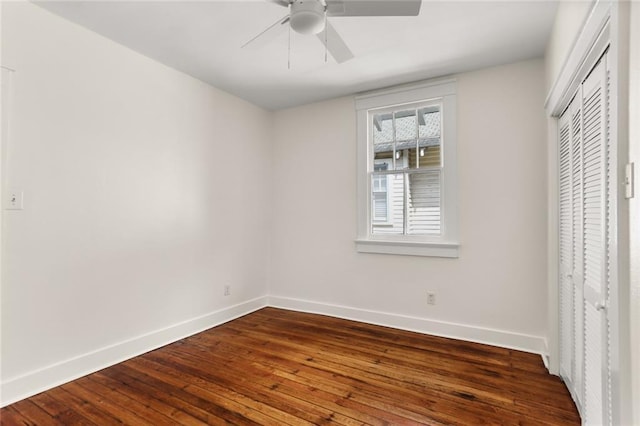 unfurnished bedroom featuring a closet, baseboards, dark wood-type flooring, and ceiling fan