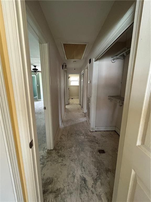 corridor with attic access and unfinished concrete flooring