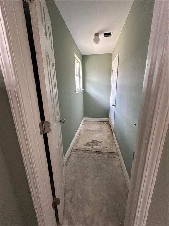 hallway featuring visible vents, unfinished concrete floors, and baseboards