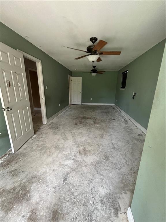 interior space featuring unfinished concrete floors, baseboards, and ceiling fan