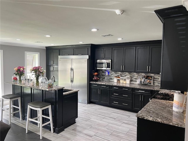 kitchen with visible vents, stone countertops, stainless steel appliances, and dark cabinetry