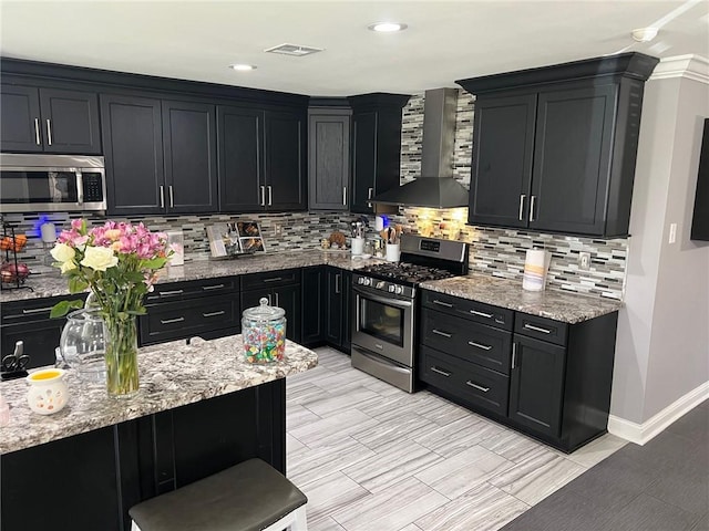 kitchen featuring tasteful backsplash, visible vents, wall chimney range hood, appliances with stainless steel finishes, and dark cabinetry