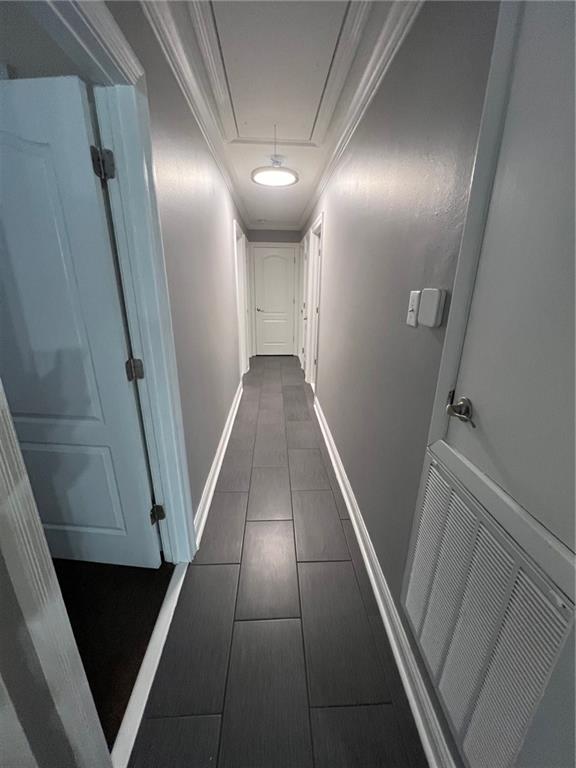 hall featuring visible vents, baseboards, attic access, and crown molding