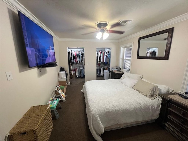 bedroom featuring two closets, ornamental molding, and carpet