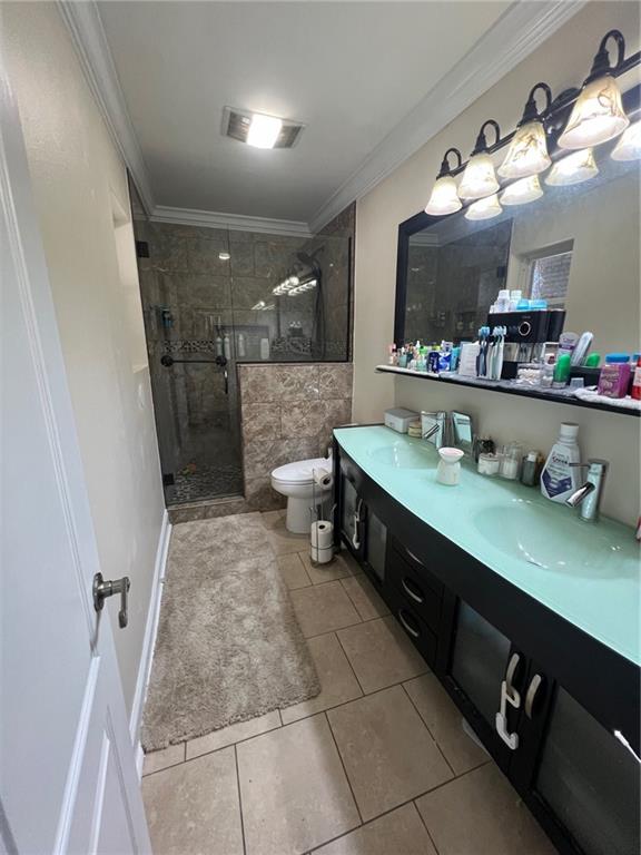 bathroom featuring crown molding, toilet, a stall shower, and a sink